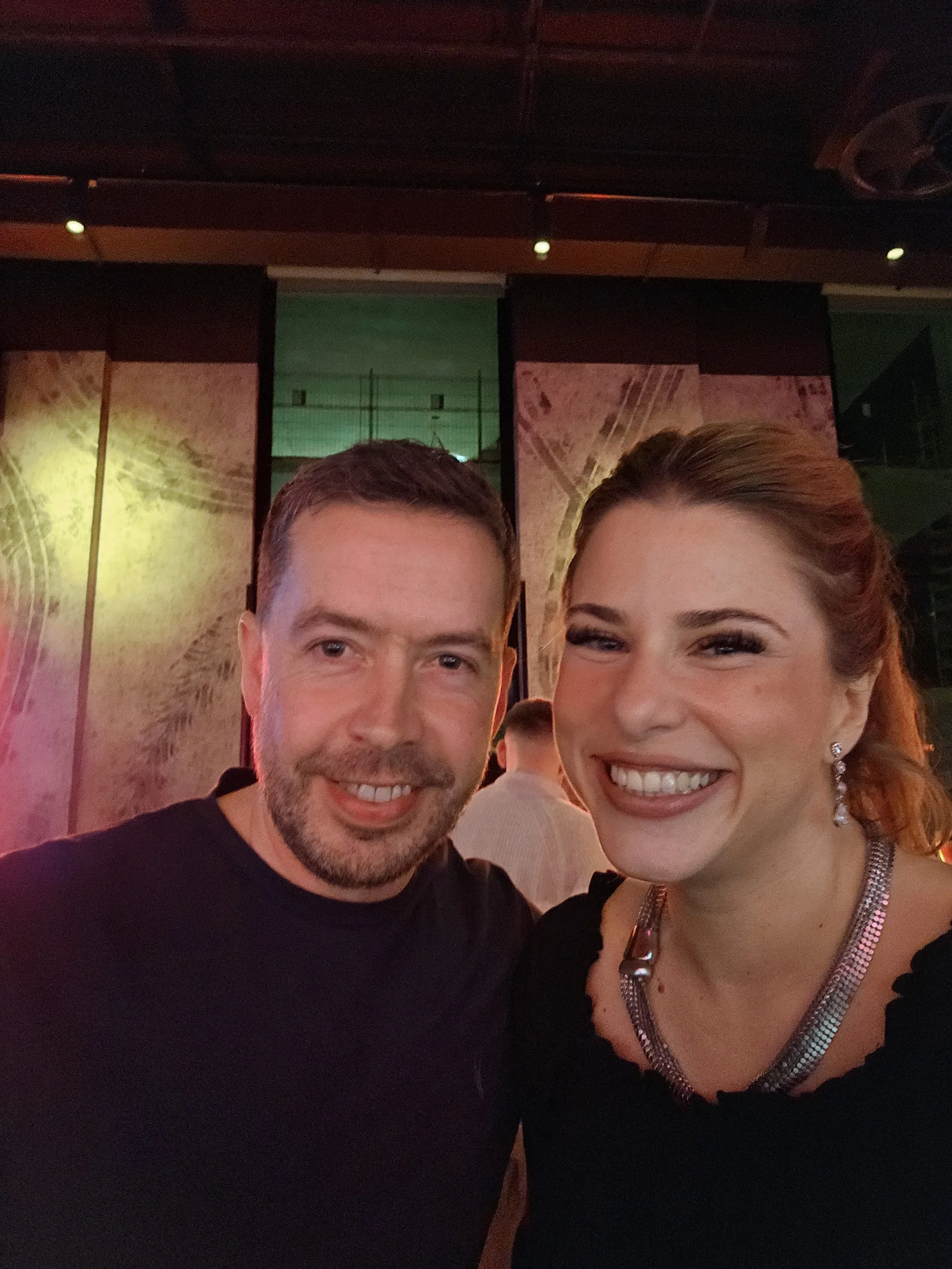 Two team members smiling together at an evening event